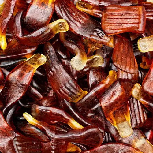 Close-up of cola-flavored gummy sweets shaped like cola bottles in rich brown and translucent yellow colors, perfect for snacking