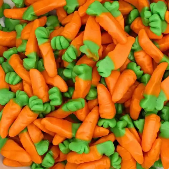 Colorful gummy carrots with orange bodies and green leafy tops, chewy orange-flavored sweets perfect for snacking
